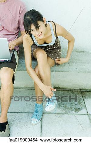 Young woman tying laces, smiling at camera View Large Photo Image Picture - Young woman tying laces, smiling at camera. Fotosearch