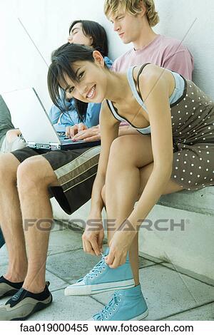 Young woman tying laces, smiling at camera View Large Photo Image Stock Photography - Young woman tying laces, smiling at camera. Fotosearch
