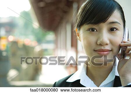 Stock Image - Young woman using cell phone, close-up. Fotosearch