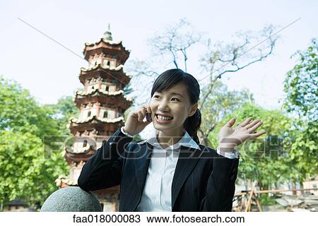 Young woman using cell phone, pagoda in background View Large Photo Image Stock Image - Young woman using cell phone, pagoda in background. Fotosearch