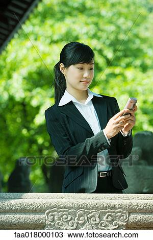 Stock Image - Young woman using cell phone. Fotosearch