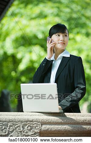 Young woman using laptop and cell phone View Large Photo Image Stock Image - Young woman using laptop and cell phone. Fotosearch