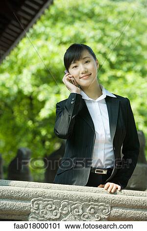 Stock Image - Young woman using laptop and cell phone. Fotosearch