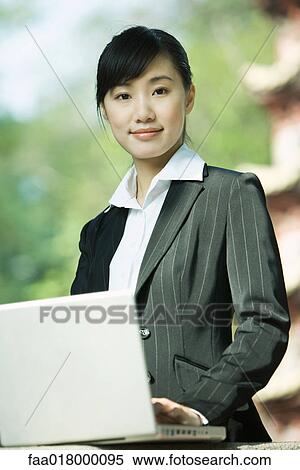 Young woman using laptop, smiling at camera, portrait View Large Photo Image Stock Photography - Young woman using laptop, smiling at camera, portrait. Fotosearch