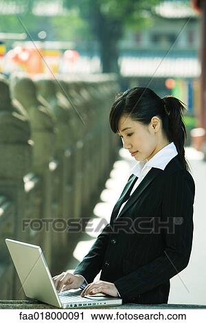 Stock Image - Young woman using laptop. Fotosearch