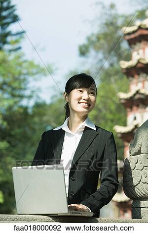Stock Image - Young woman using laptop. Fotosearch