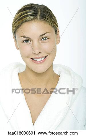 Stock Image - Young woman wearing bathrobe, smiling at camera, portrait. Fotosearch
