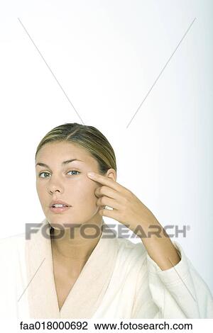 Young woman wearing bathrobe, touching corner of eye View Large Photo Image Stock Image - Young woman wearing bathrobe, touching corner of eye. Fotosearch