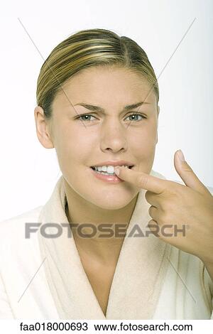 Young woman wearing bathrobe, touching teeth and furrowing brow View Large Photo Image Stock Image - Young woman wearing bathrobe, touching teeth and furrowing brow. Fotosearch