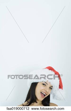 Young woman wearing santa hat, portrait View Large Photo Image Stock Image - Young woman wearing santa hat, portrait. Fotosearch