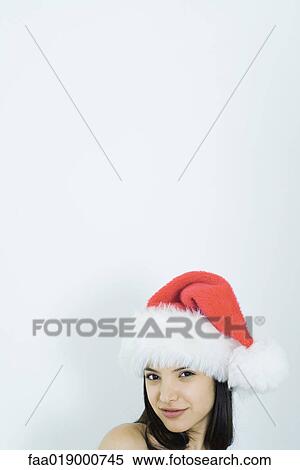 Stock Photography - Young woman wearing santa hat, portrait. Fotosearch