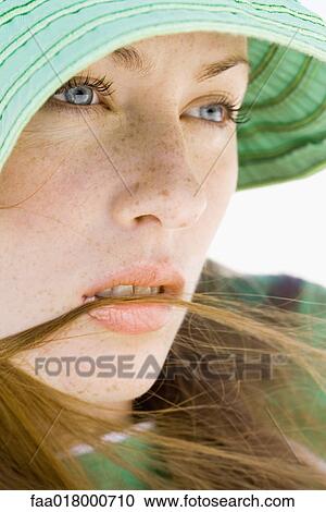 Stock Image - Young woman wearing sun hat, close-up . Fotosearch