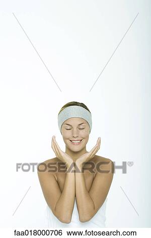 Stock Photograph - Young woman with dots of moisturizer under eye, eyes closed, hands around face. Fotosearch