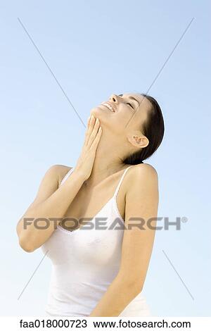 Stock Image - Young woman with eyes closed and head back, hand on neck. Fotosearch