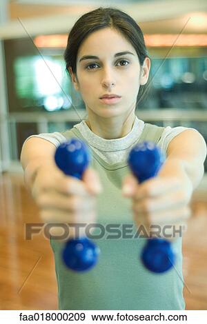 Stock Photo - Young woman working out with dumbbells. Fotosearch