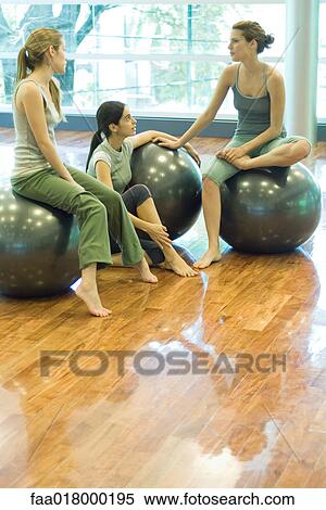Stock Photography - Young women sitting on fitness balls, chatting. Fotosearch