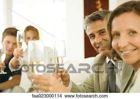 Adult friends making a toast with champagne, smiling at camera View Large Photo Image Picture - Adult friends making a toast with champagne, smiling at camera. Fotosearch