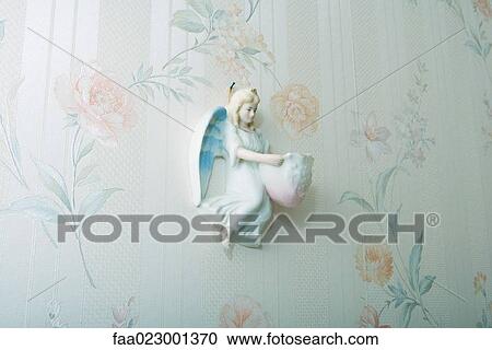 Stock Image - Angel knickknack hanging on wall. Fotosearch