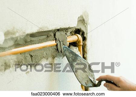 Applying plaster over pipe in wall, close-up View Large Photo Image Stock Photograph - Applying plaster over pipe in wall, close-up. Fotosearch