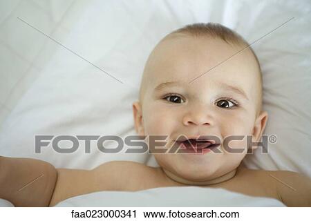 Baby in bed, under covers, smiling View Large Photo Image Stock Image - Baby in bed, under covers, smiling. Fotosearch