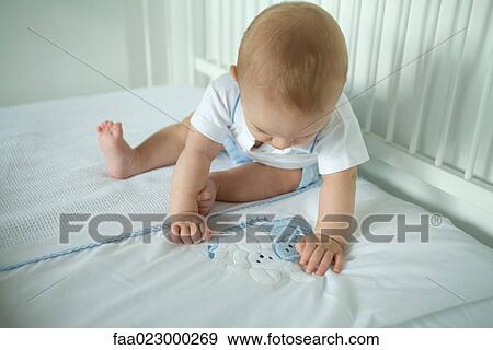 Stock Photo - Baby in crib, looking at bunnies on blanket. Fotosearch