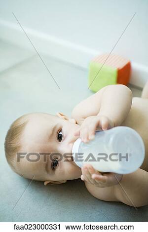 Baby lying on floor, drinking from bottle View Large Photo Image Stock Image - Baby lying on floor, drinking from bottle. Fotosearch