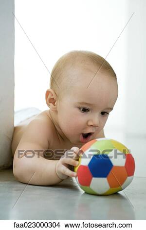 Baby lying on floor, holding ball, mouth wide open View Large Photo Image Picture - Baby lying on floor, holding ball, mouth wide open. Fotosearch