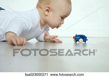 Baby lying on floor, looking at toy airplane View Large Photo Image Stock Image - Baby lying on floor, looking at toy airplane. Fotosearch