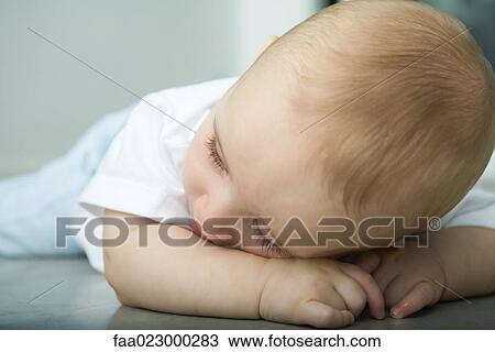 Baby lying on floor, resting head on arm View Large Photo Image Stock Image - Baby lying on floor, resting head on arm. Fotosearch