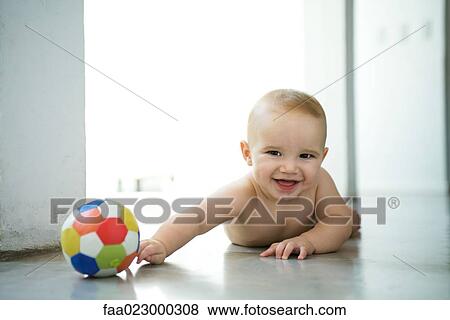Baby lying on floor with ball, laughing and looking at camera View Large Photo Image Stock Photo - Baby lying on floor with ball, laughing and looking at camera. Fotosearch