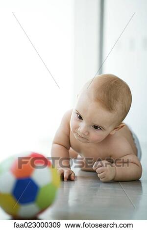 Baby on floor, looking at ball in blurred foreground View Large Photo Image Stock Photo - Baby on floor, looking at ball in blurred foreground. Fotosearch