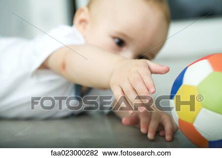 Stock Image - Baby on floor, reaching for ball. Fotosearch