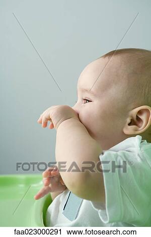 Baby sitting in high chair, wiping face View Large Photo Image Stock Image - Baby sitting in high chair, wiping face. Fotosearch