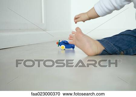 Baby sitting on floor, reaching for toy airplane, low section View Large Photo Image Stock Image - Baby sitting on floor, reaching for toy airplane, low section. Fotosearch