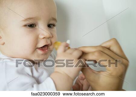 Baby taking pacifier from mother's hand, close-up View Large Photo Image Stock Photo - Baby taking pacifier from mother's hand, close-up. Fotosearch