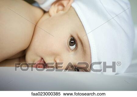 Baby wearing cap, lying down, looking at camera, close-up View Large Photo Image Stock Photography - Baby wearing cap, lying down, looking at camera, close-up. Fotosearch