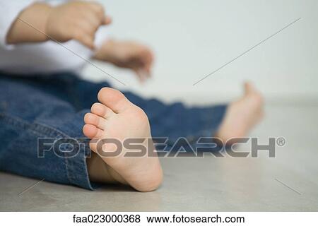 Baby wearing jeans, sitting on floor, low section, focus on foreground View Large Photo Image Stock Photo - Baby wearing jeans, sitting on floor, low section, focus on foreground. Fotosearch