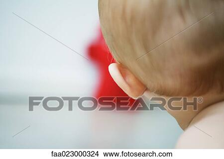 Baby with head turned toward toy, rear cropped view, close-up View Large Photo Image Picture - Baby with head turned toward toy, rear cropped view, close-up. Fotosearch