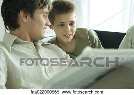 Boy and father reading newspaper together on sofa View Large Photo Image Stock Photography - Boy and father reading newspaper together on sofa. Fotosearch