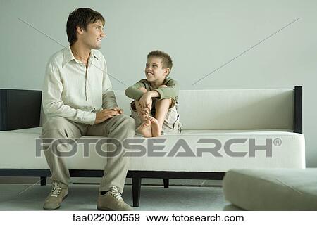 Boy and father sitting on sofa, talking View Large Photo Image Stock Photo - Boy and father sitting on sofa, talking. Fotosearch