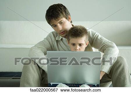 Boy and father using laptop together View Large Photo Image Stock Photo - Boy and father using laptop together. Fotosearch