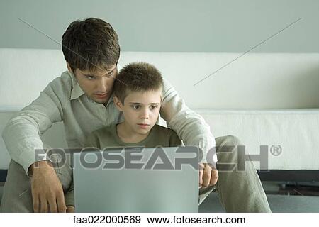 Boy and father using laptop together View Large Photo Image Stock Photo - Boy and father using laptop together. Fotosearch