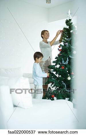 Boy and mother decorating Christmas tree View Large Photo Image Stock Photo - Boy and mother decorating Christmas tree. Fotosearch