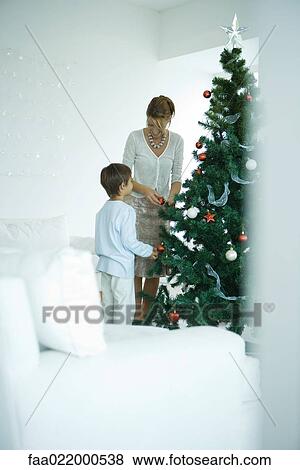 Boy and mother decorating Christmas tree View Large Photo Image Stock Photo - Boy and mother decorating Christmas tree. Fotosearch