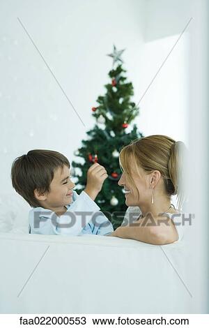 Boy and mother on sofa smiling at each other, Christmas tree in background View Large Photo Image Stock Image - Boy and mother on sofa smiling at each other, Christmas tree in background. Fotosearch
