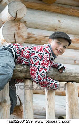 Boy climbing on rail in front of log cabin, smiling at camera View Large Photo Image Stock Photo - Boy climbing on rail in front of log cabin, smiling at camera. Fotosearch