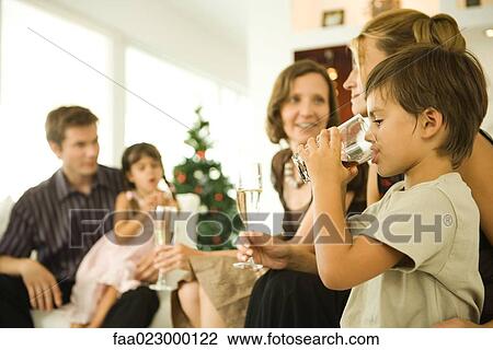 Boy drinking beverage, adults drinking champagne, Christmas tree in background View Large Photo Image Stock Image - Boy drinking beverage, adults drinking champagne, Christmas tree in background. Fotosearch