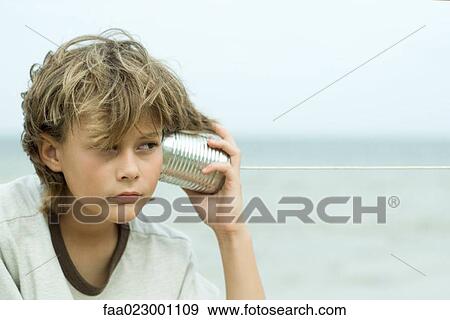 Boy holding tin can phone up to ear, looking away, portrait View Large Photo Image Stock Photo - Boy holding tin can phone up to ear, looking away, portrait. Fotosearch