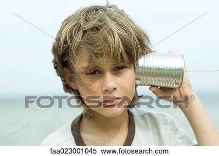 Boy holding tin can phone up to ear, looking at camera, portrait View Large Photo Image Stock Photography - Boy holding tin can phone up to ear, looking at camera, portrait. Fotosearch