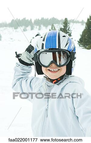 Stock Photo - Boy holding up snowball, dressed in ski clothing, smiling at camera. Fotosearch